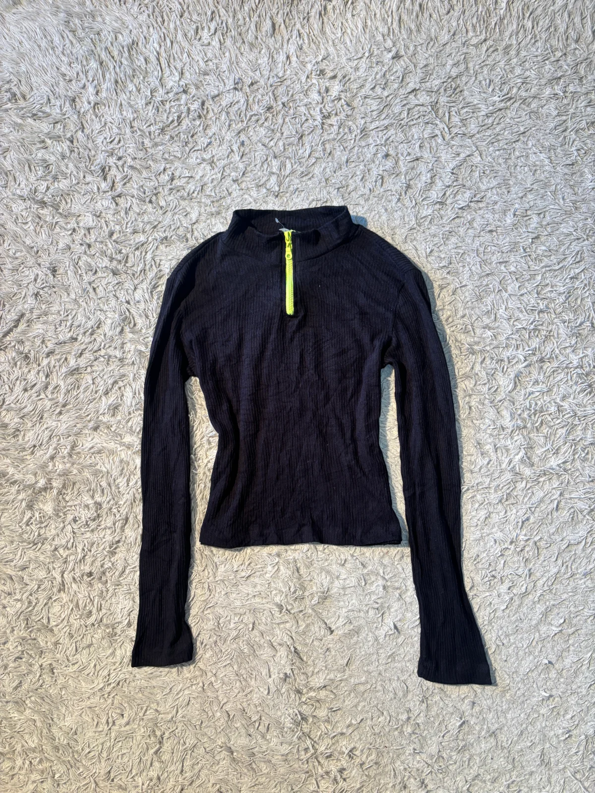 black ribbed top features a prominent neon green zipper on the mock neck
